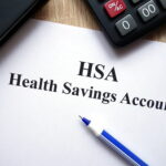 HSA health savings account document, calculator, pen and glasses on desk